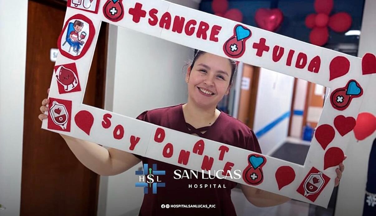 Colaboradora del Hospital San Lucas sosteniendo el marco de la campaña de donación de sangre