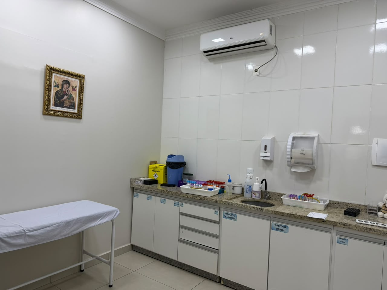 Sala de toma de muestras del laboratorio con camilla, tubos de extracción y mesada de trabajo